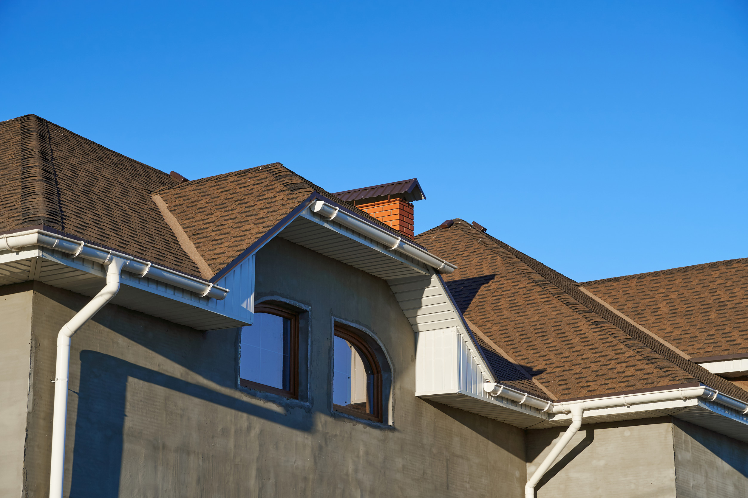 Toit en tuiles brun avec gouttières blanches